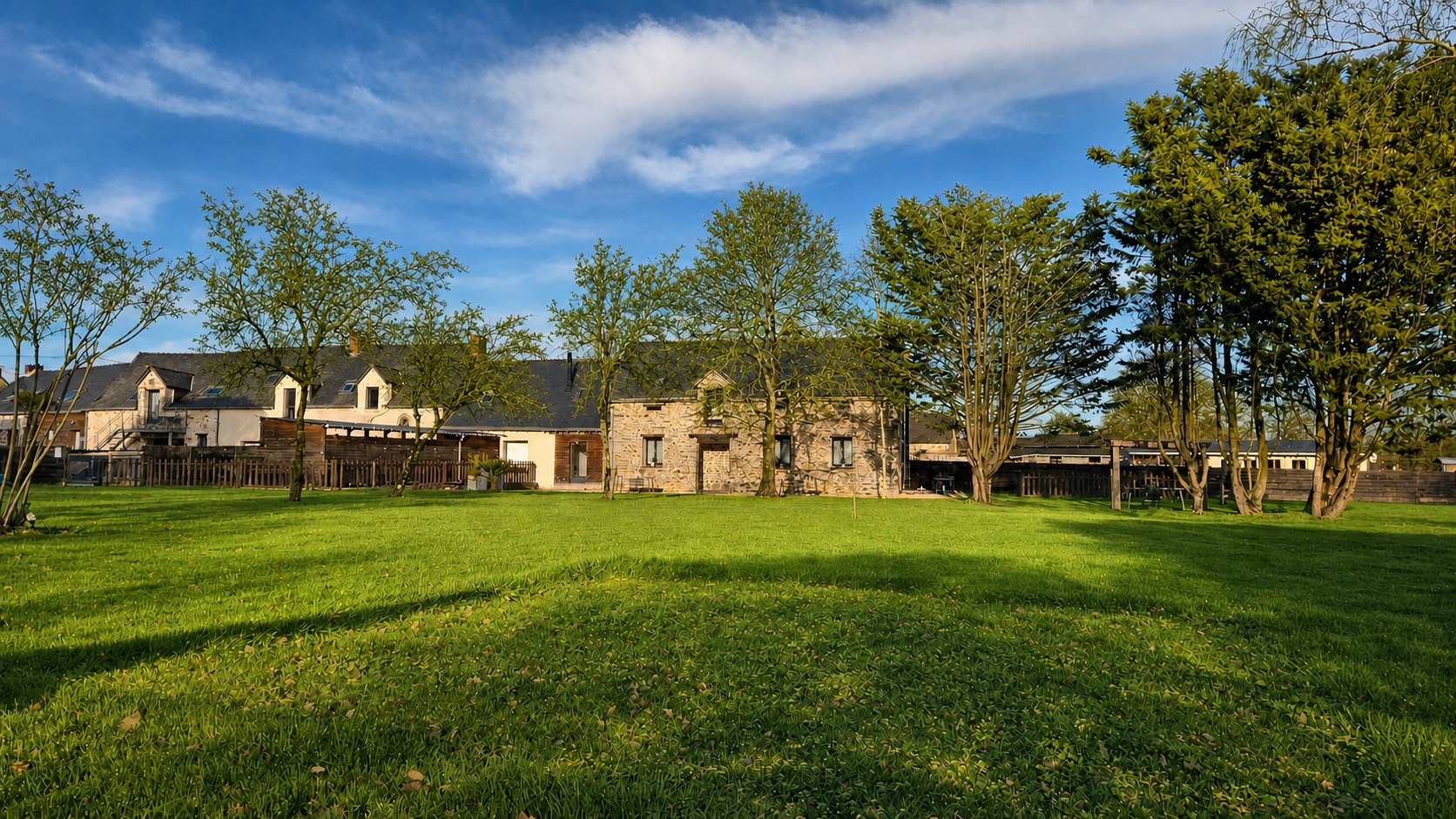 La façade en pierre des Gîtes du Petit Marcel dans son parc en été