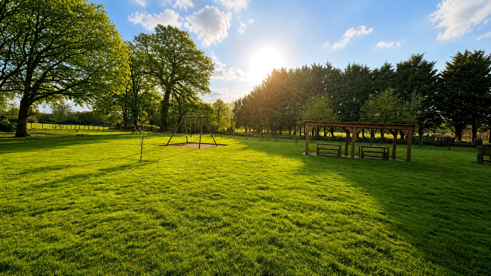 Une vue large et lumineuse du parc arboré des Gîtes du Petit Marcel