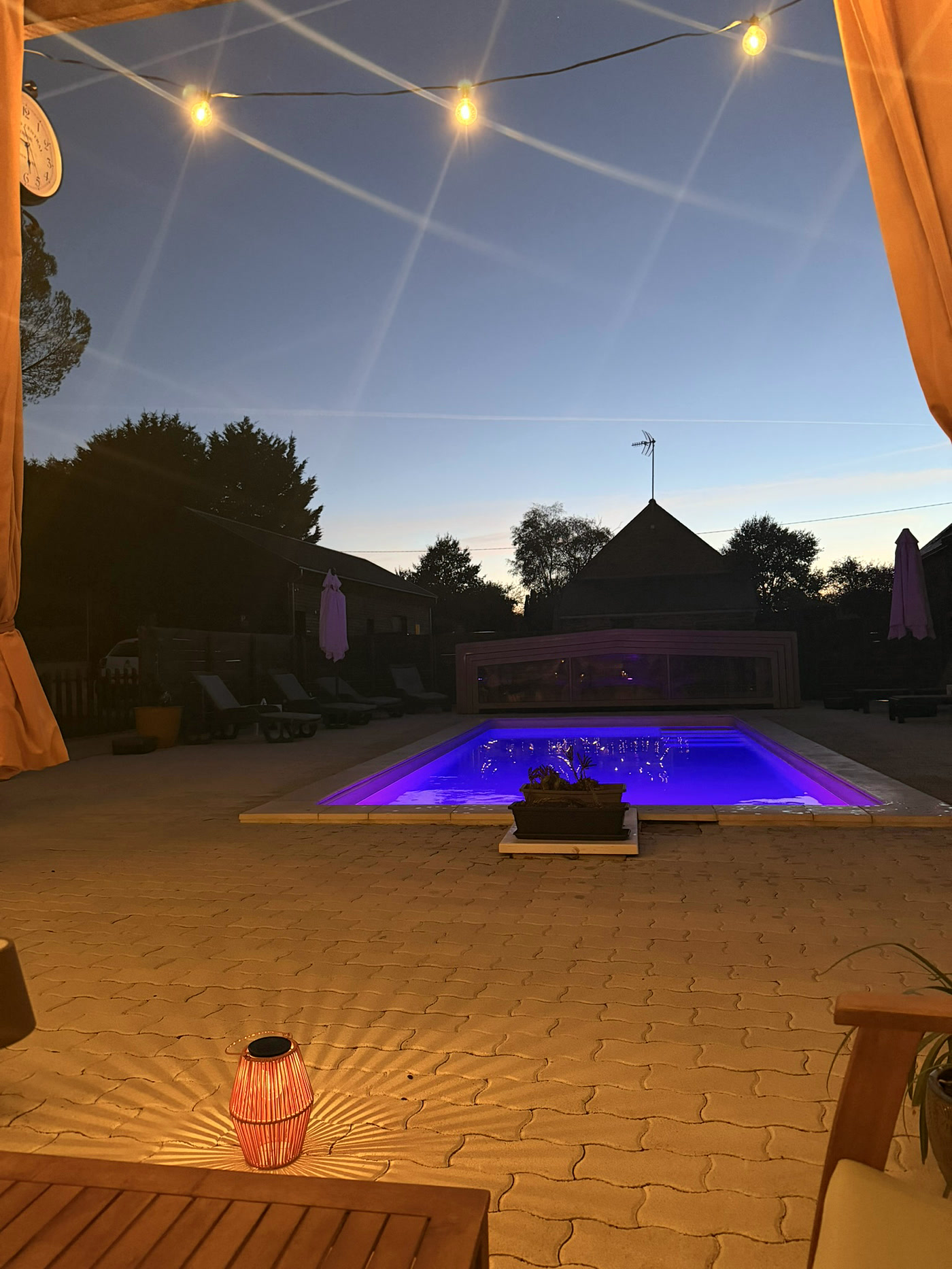 La piscine éclairée vue depuis la terrasse du bar