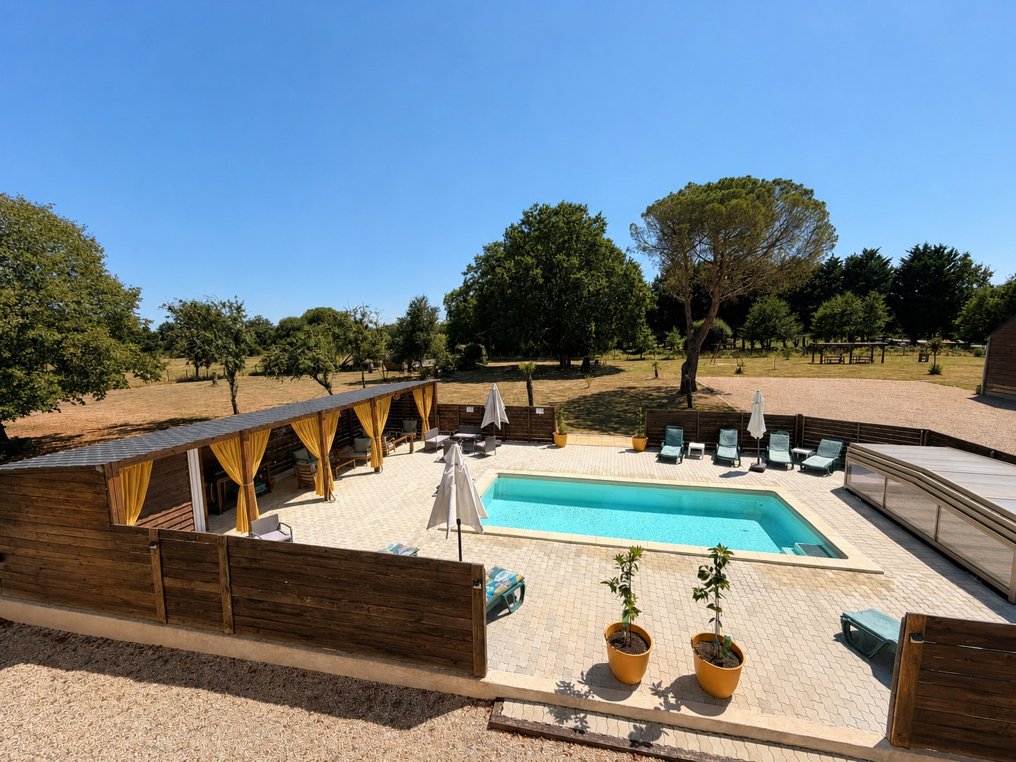La piscine chauffée et le bar d’été aux rideaux jaune ocre